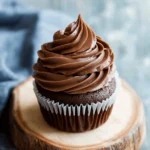 š« Creamy Chocolate Frosting Recipe: A Rich, Velvety Classic 2 Chocolate cupcake topped with rich, swirled chocolate frosting on a rustic wood slice.