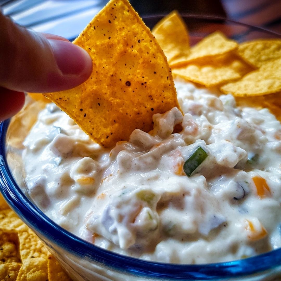 Dorito Chip Being Dipped Into Homemade Creamy Dip Dipping a Dorito chip into creamy homemade Doritos dip